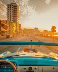 City street by buildings against sky during sunset