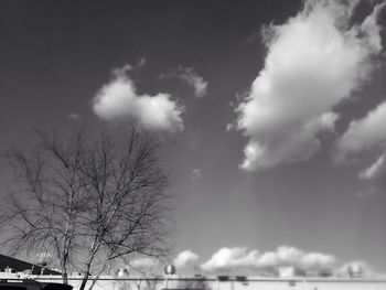 Low angle view of bare trees against cloudy sky