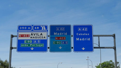 Low angle view of road signs against blue sky