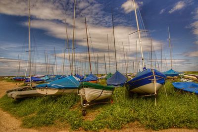 Sailboats moored on field against sky