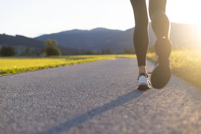 Jogging concept. low section of woman running on rural path on sunset