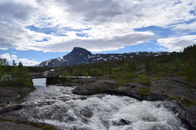 Scenic view of river by mountains against sky