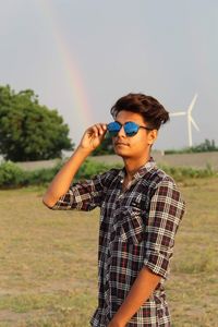 Boy wearing sunglasses standing on field