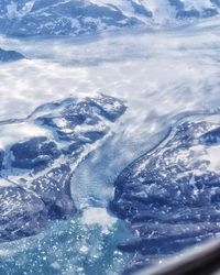 Aerial view of snowcapped mountains by sea against sky