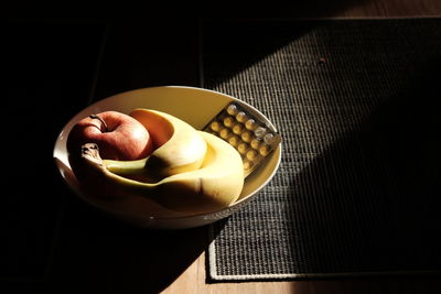 High angle view of fruits with medicines in bowl on table