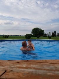 People swimming in pool against sky