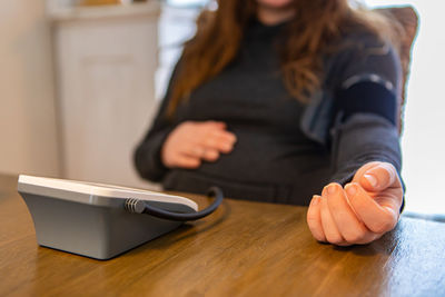 Midsection of woman checking blood pressure at home