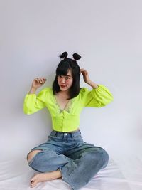 Portrait of young woman sitting against white background
