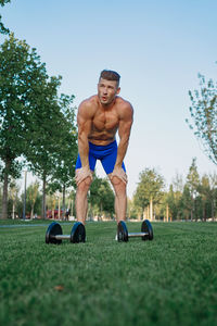 Portrait of shirtless man exercising in park