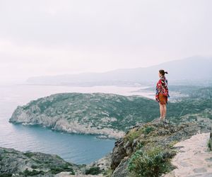 Woman standing on mountain by sea against sky