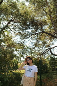 Portrait of smiling young woman standing against trees