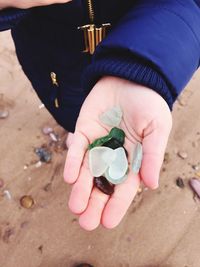 Low section of woman gemstones on sandy beach