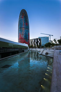 View of swimming pool in city against clear blue sky