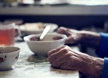 Close-up of senile sinewy hands at the dinner table.