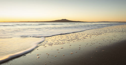 Scenic view of beach against clear sky during sunset