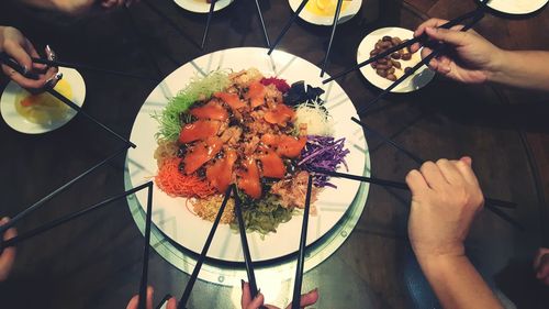 Cropped hands having food with chopsticks