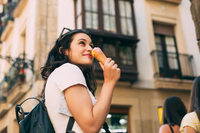 Portrait of woman holding ice cream in city