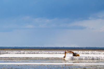 Construction machinery on frozen land against sky