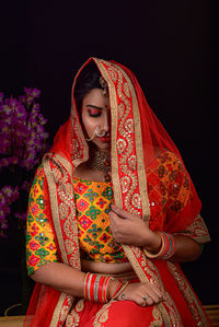 Portrait of young woman standing against black background