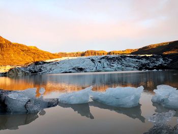 Scenic view of lake by snowcapped mountains against sky during winter