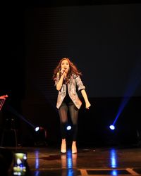 Full length of woman standing against illuminated lights at night