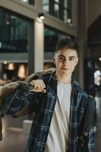 Portrait of smiling boy carrying luggage while standing at station