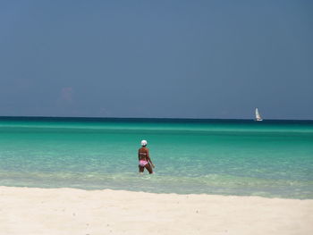 Rear view of man overlooking calm blue sea