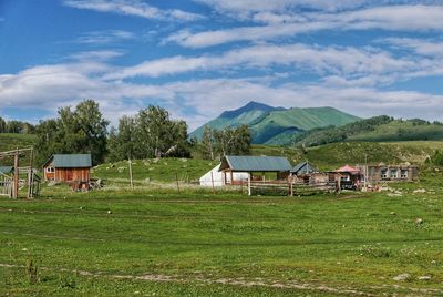 Houses by agricultural field against sky