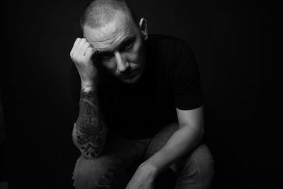 Full length of man sitting against black background