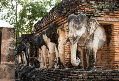 Close-up animal statue amidst old brick wall 