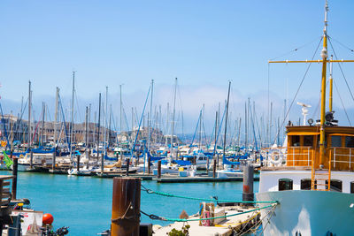 Sailboats moored at harbor against clear blue sky