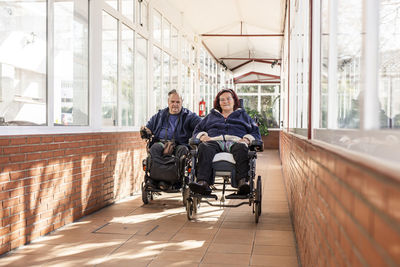 Disabled man and woman on wheelchair in corridor