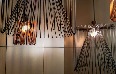 Low angle view of illuminated pendant lights hanging on wall at home