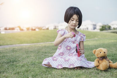 Cute girl sitting with toy on field