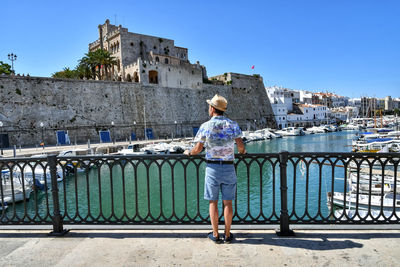 Rear view of boy standing in city against clear sky