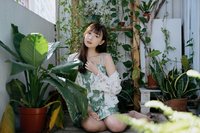 Portrait of young woman standing by plants