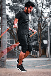 Asian sportsman training with jumping rope in the park.