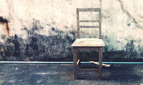 Empty chairs and table against wall