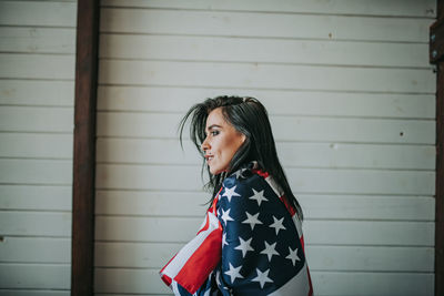 Woman with american flag against wall