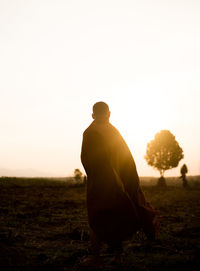 Rear view of man standing on field against sky