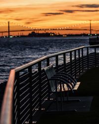 Close-up of railing against sea during sunset