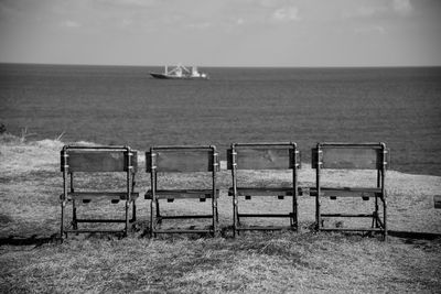 Row of chairs by the sea against sky