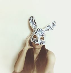 Portrait of woman wearing mask against wall