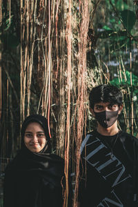 Portrait of young couple standing in forest