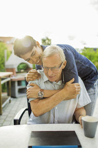 Happy young man embracing grandfather at yard