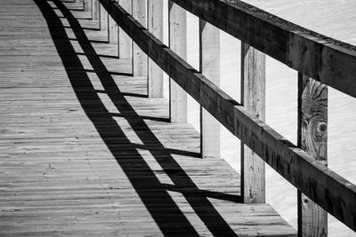 High angle view of railing shadow on pier at beach