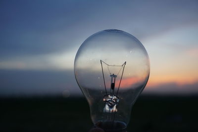 Close-up of light bulb against sky during sunset