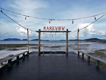 Information sign on shore against sky