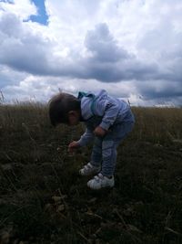 Boy standing on field against sky