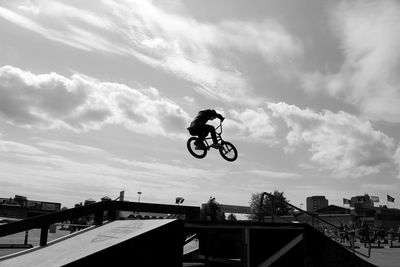 Low angle view of man performing stunt with bicycle in park against sky